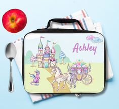 a lunch box with an apple, spoon and napkins next to it on a blue background