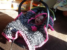 a baby sitting in a stroller with a blanket on it's head and mouth