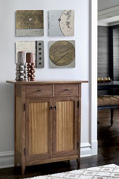 a wooden cabinet sitting on top of a hard wood floor next to a white wall