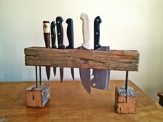 several knives are placed on top of a piece of wood with wooden block holders holding them