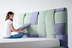 a woman sitting on top of a bed next to a green and blue headboard