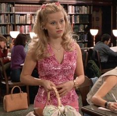 a woman in a pink dress holding a basket and sitting at a table with other people