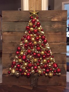 a christmas tree made out of wooden pallets with red and gold ornaments on it