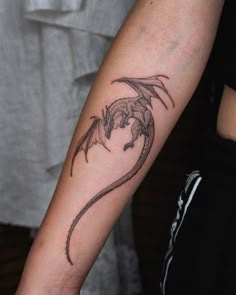 a woman with a dragon tattoo on her arm, holding onto the arm of another person's arm