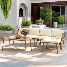 a white couch sitting on top of a wooden table next to a planter filled with flowers