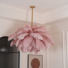 a pink chandelier hanging from the ceiling in a room with pictures on the wall