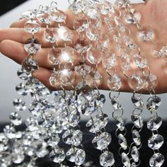 a person holding some clear crystal beads in their hand and the other hand is full of them