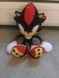 sonic the hedgehog plush toy sitting on the floor next to a white and black door