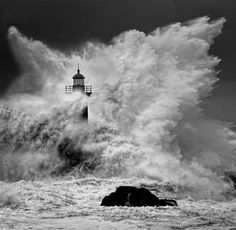 a lighthouse surrounded by large waves in the ocean