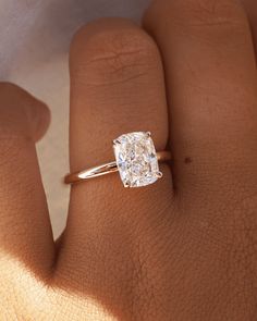 a woman's hand with a diamond ring on top of her finger, showing the center stone