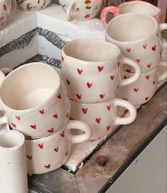 many white cups with red hearts on them are sitting on a table next to each other