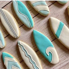 decorated cookies with blue and white icing are arranged on a wooden surface, including surfboards