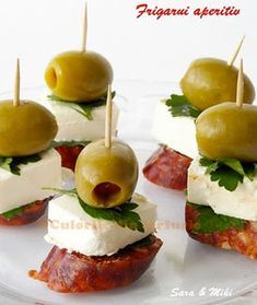 small appetizers with olives, cheese and meat on them sitting on a white plate