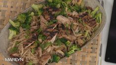 a bowl filled with meat and broccoli on top of a table next to a cell phone