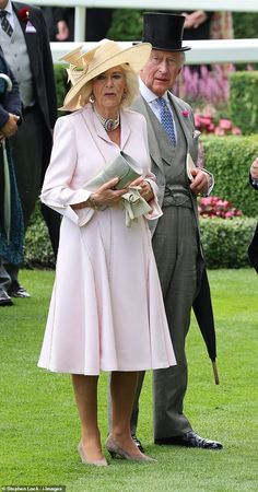 an older man and woman dressed in formal attire standing next to each other on the grass