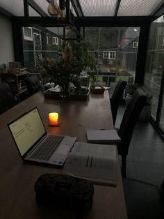 an open laptop computer sitting on top of a wooden table next to a lit candle