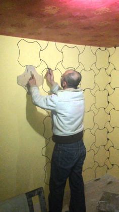 a man painting a wall with yellow paint