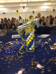 a vase filled with balloons and confetti on top of a blue table cloth