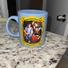 a blue coffee mug with the cast of friends on it sitting on a kitchen counter