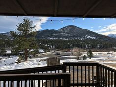 a balcony with snow covered mountains and lights strung from the ceiling, overlooking a parking lot