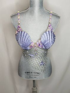 a mannequin wearing a purple and silver bralet with seashells on it