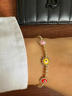 Add a touch of color and charm to your jewelry collection with this beautiful Evil Eye Flower Bracelet. Featuring a delicate gold-plated chain adorned with vibrant enamel evil eye charms nestled within small flowers, this versatile accessory is perfect for any outfit. The evil eye, a powerful symbol of protection, is combined with a floral design to create a boho-chic vibe. Crafted with high-quality materials, this bracelet is both stylish and meaningful—a perfect gift for yourself or a loved one. 🌼💫 Multicolor Dainty Jewelry With Flower Charm, Dainty Multicolor Flower Jewelry, Yellow Adjustable Chain Bracelet, Yellow Adjustable Bracelet, Yellow Flower Shaped Jewelry With Adjustable Chain, Multicolor Flower Shaped Jewelry With Charms, Multicolor Flower-shaped Jewelry With Charms, Evil Eye Flower, Colorful Evil Eye