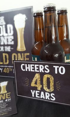 there are four bottles of beer on the table and two signs that say cheers to 40 years