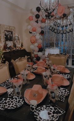 the table is set with black and white plates, orange napkins, and balloons