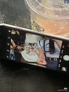 a cell phone sitting on top of a table next to a cup