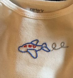 a white shirt with a blue and red airplane embroidered on the chest, along with words that read'care '