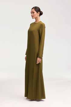 Indulge in luxury with the Estee Viscose Maxi Dress in Olive Night. Crafted with breezy viscose material, this dress boasts a modest fit and straight sleeves perfect for the summer. Dress it up or down and enjoy the ultimate comfort and effortless style no matter the occasion. Elevate your wardrobe with this exquisite piece. Model is 5'7" and is wearing size XS/58". Green Long Sleeve Maxi Dress With Side Slits, Solid Maxi Dress With Modesty Panel, Long Rayon Daywear Dresses, Long Rayon Dresses For Daywear, Long Dress With Modesty Panel, Elegant Long Maxi Dress With Modesty Panel, Elegant Green Rayon Dress, Silk Long Sleeve Dresses With Side Slits, Green Rayon Long Sleeve Maxi Dress