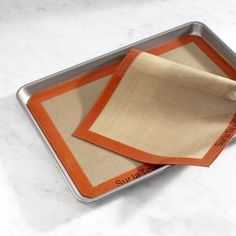 there are two pieces of paper on top of each other in a metal tray with an orange border