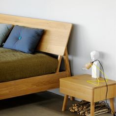 a wooden bed sitting next to a night stand with two pillows on top of it