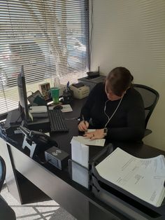 a person sitting at a desk with a pen and paper in front of them, writing