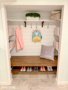 a wooden bench sitting in front of a white wall filled with shelves and shoes on top of it