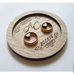 two wedding rings sitting on top of a wooden coaster