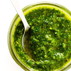 a spoon in a jar filled with pesto