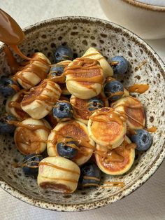 a bowl filled with pancakes and blueberries covered in syrup