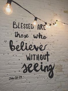 a white brick wall with some lights on it and the words, blessing are those who believe