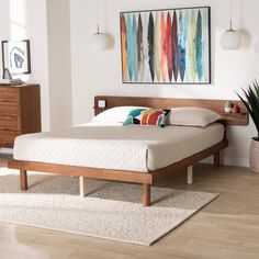 a bed sitting on top of a wooden floor next to a dresser and lamp above it