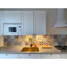 a kitchen with white cupboards and an oven above the sink, next to a stove top