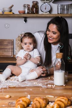 a woman holding a baby while sitting on the floor next to some doughnuts