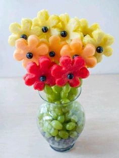 a vase filled with fruit and flowers on top of a table