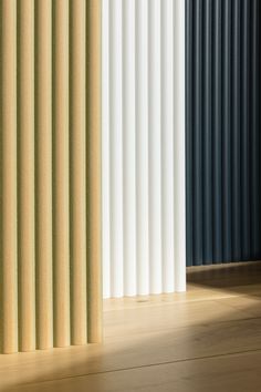 an empty room with vertical blinds on the wall and wood flooring in front of it