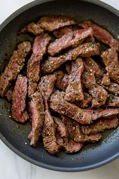 steak in a skillet with seasoning on the side, ready to be cooked