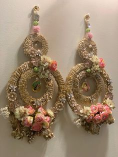 two pairs of earrings with flowers on them hanging from the wall next to each other