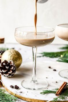 two glasses filled with liquid and topped with pine cones, cinnamon sticks and christmas decorations