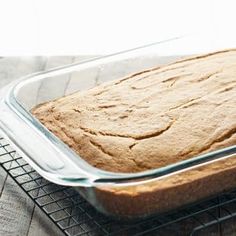 a loaf of bread sitting on top of a cooling rack next to a glass pan