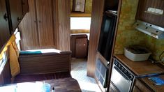 the interior of a motor home with wood paneling and cabinets, including an oven