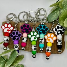 several key chains with different colored paw prints on them, hanging from a wooden holder